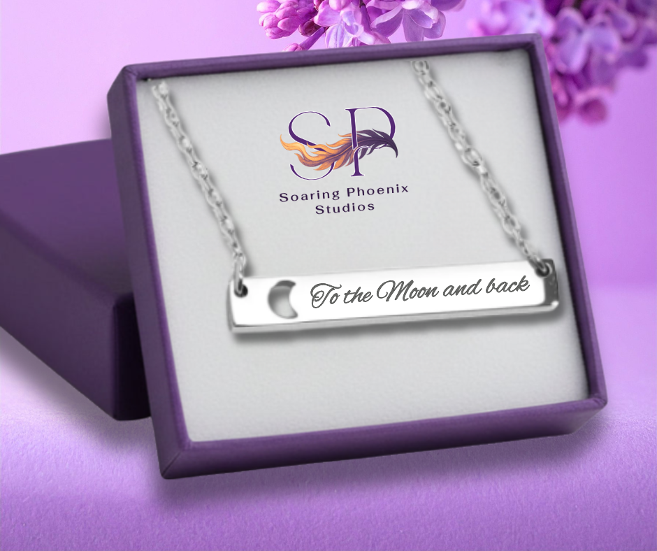Necklace with 'To the Moon and back' engraving in a Soaring Phoenix Studios box on a purple background