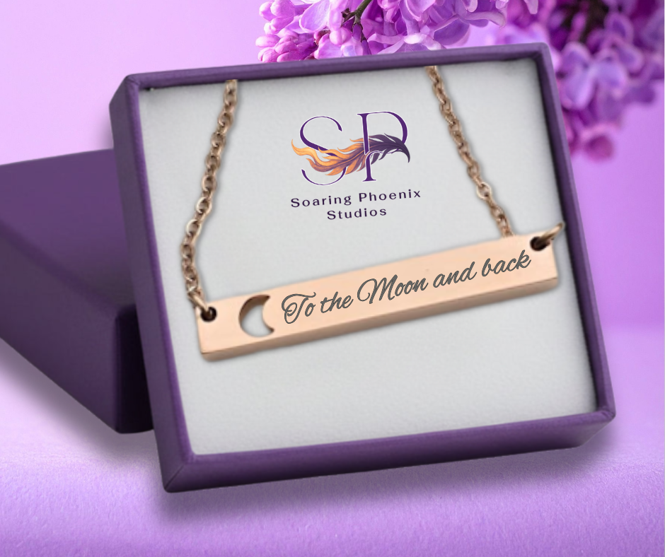 Necklace with 'To the Moon and back' engraving in a Soaring Phoenix Studios box on a purple background